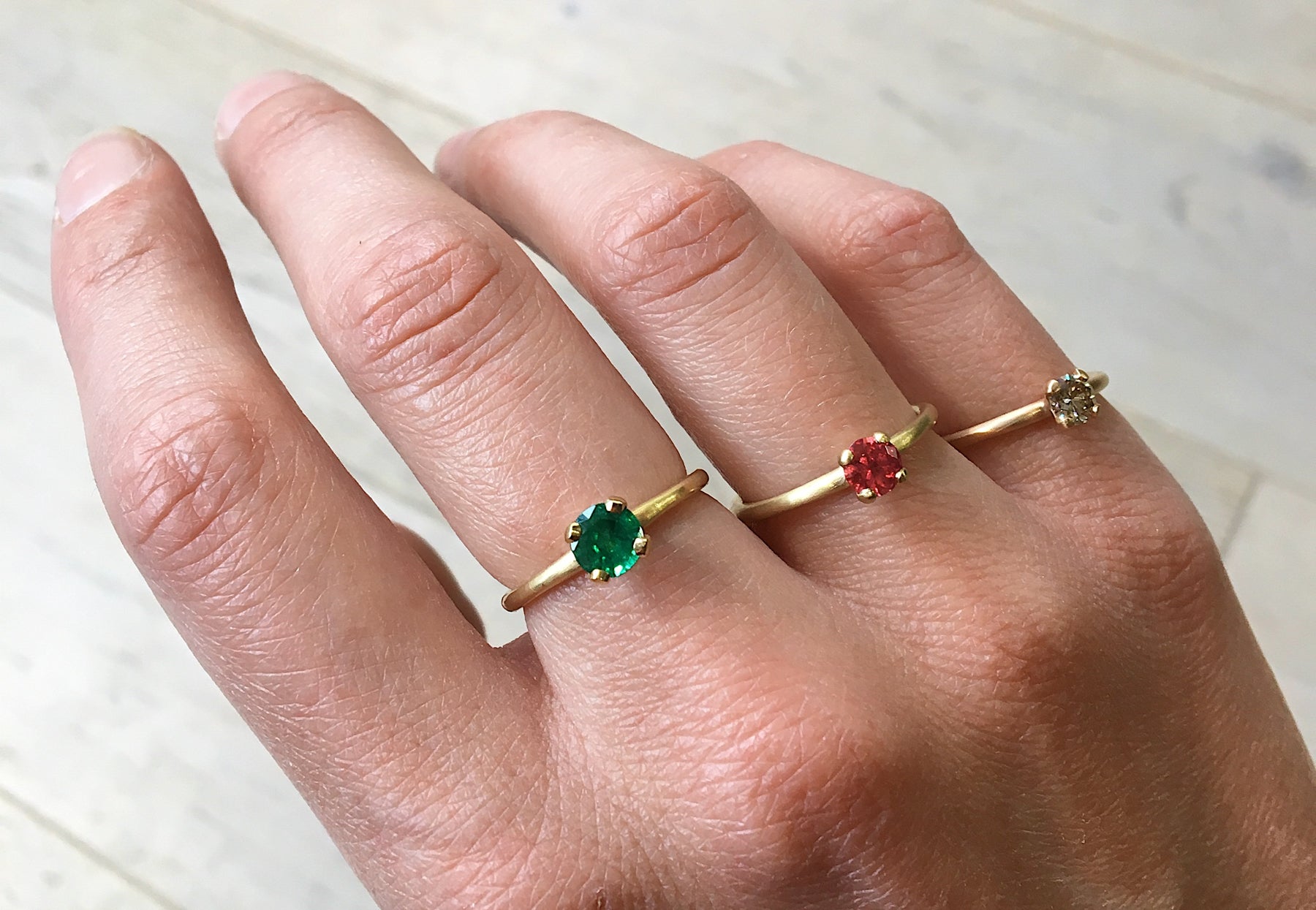 4 claw emerald, ruby and cognac diamond rose gold engagement rings on hand